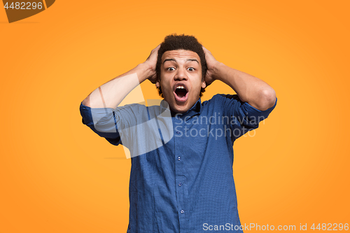 Image of The young attractive man looking suprised isolated on orange