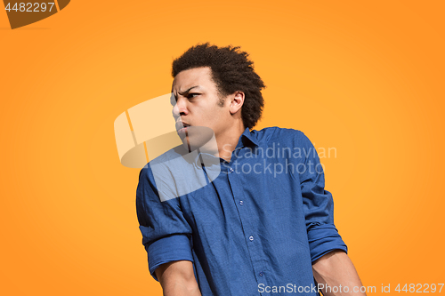 Image of Let me think. Doubtful pensive man with thoughtful expression making choice against orange background