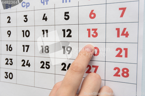 Image of Hand pointing to the day off Saturday on a wall calendar