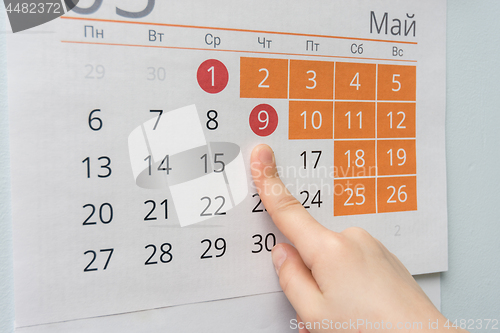 Image of Children\'s hand points to the long May holidays holiday in the wall calendar