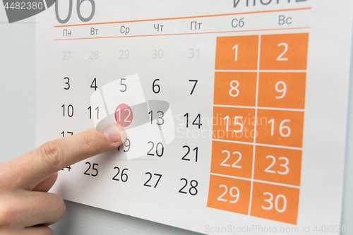 Image of Finger points to a holiday in the wall calendar