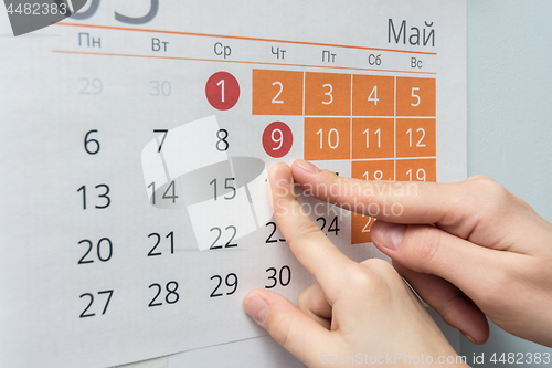 Image of Child and adult hands indicate the date of May 9 wall calendar