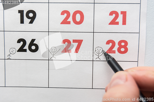 Image of A pencil draws funny people on a sheet of a wall calendar