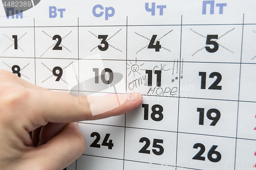 Image of Hand indicates the day on the calendar with the inscription vacation