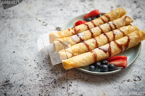 Image of Plate of delicious crepes roll with fresh fruits and chocolate