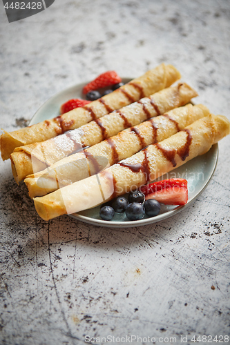 Image of Plate of delicious crepes roll with fresh fruits and chocolate