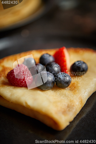 Image of Close up on pancake with fresh fruit topping placed on dark rusty table