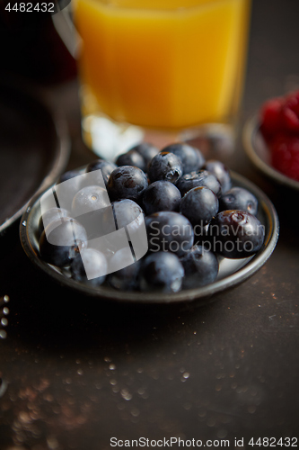 Image of Close up on fresh blueberries placed on ceramic saucer on dark rusty table