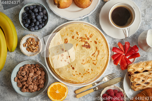 Image of Breakfast table setting with fresh fruits, pancakes, coffee, croissants