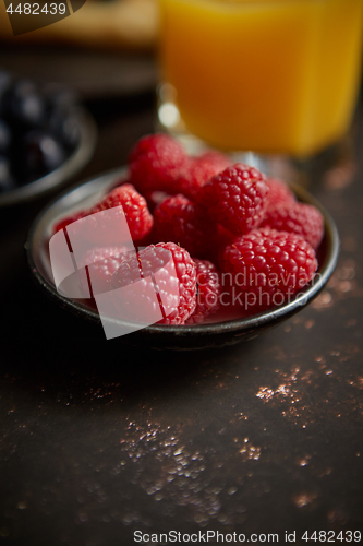 Image of Close up on fresh raspberries placed on ceramic saucer on dark rusty table.