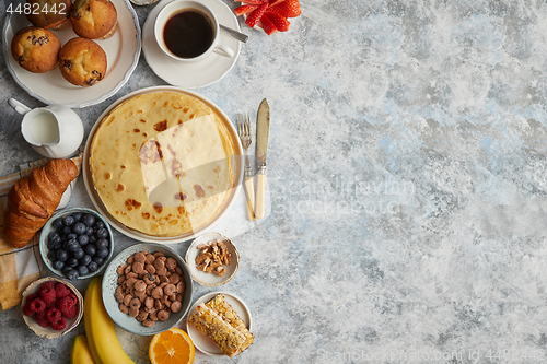 Image of Breakfast table setting with fresh fruits, pancakes, coffee, cro