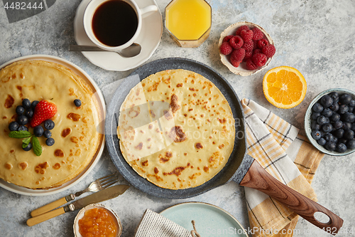 Image of Delicious pancakes on stone frying pan. Placed on table with various ingredients