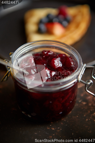 Image of Close up on jar filled with fresh cherry marmalade placed on dark rusty table