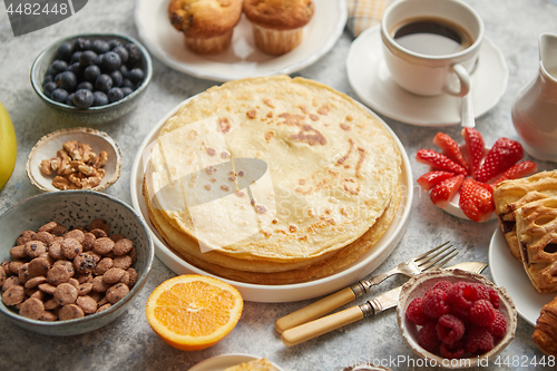 Image of Breakfast table setting with fresh fruits, pancakes, coffee, croissants