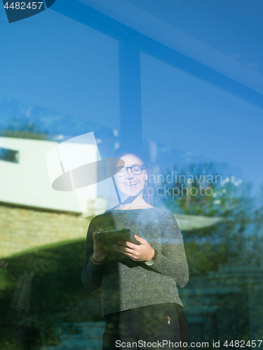 Image of Woman using tablet at home by the window