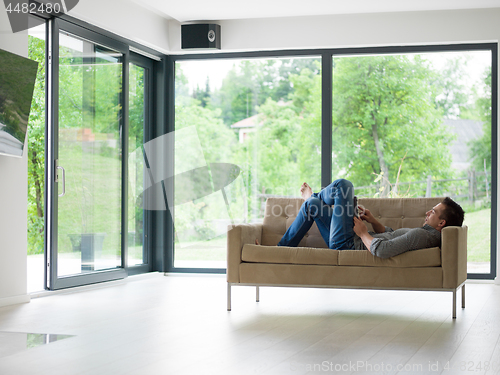 Image of man on sofa using tablet computer