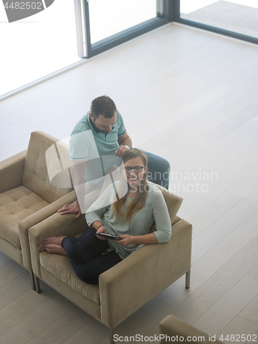 Image of couple relaxing at  home with tablet computers