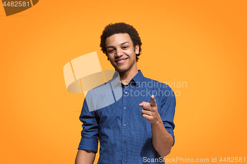 Image of The happy business man point you and want you, half length closeup portrait on orange background.