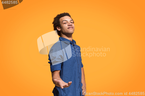 Image of Beautiful male half-length portrait isolated on orange studio backgroud. The young emotional surprised man