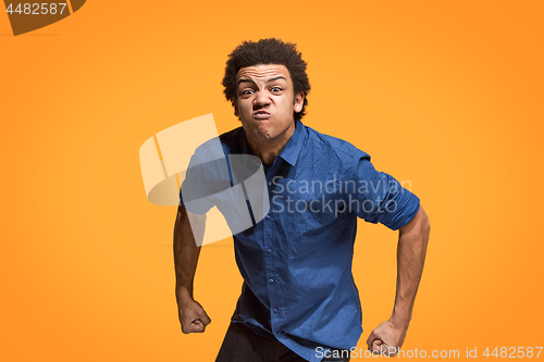 Image of The young emotional angry man screaming on orange studio background