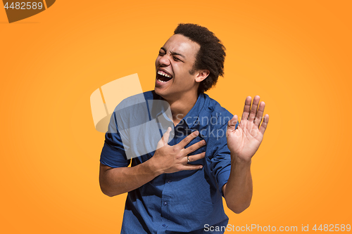Image of The happy business man standing and smiling against orange background.