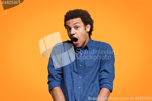 Image of The young attractive man looking suprised isolated on orange