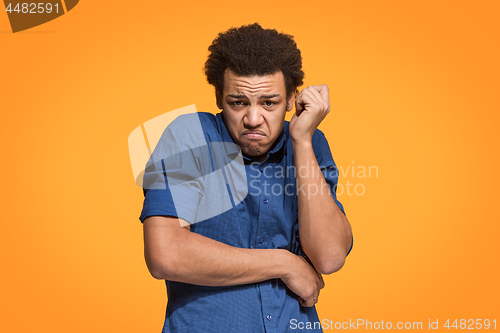 Image of Let me think. Doubtful pensive man with thoughtful expression making choice against orange background