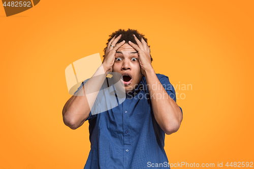 Image of The young emotional angry man screaming on orange studio background