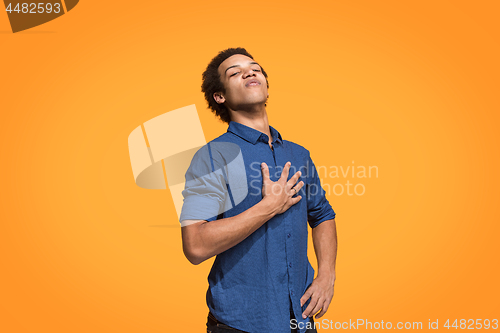 Image of Beautiful male half-length portrait isolated on orange studio backgroud. The young emotional surprised man