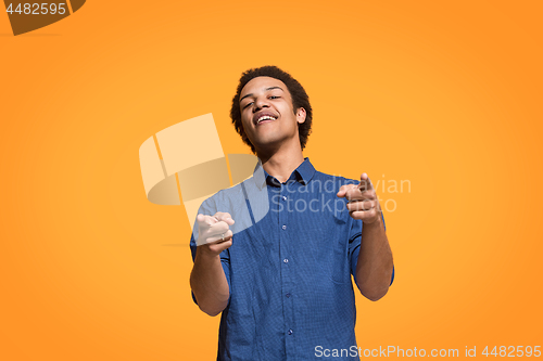 Image of The happy business man point you and want you, half length closeup portrait on orange background.