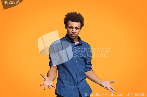 Image of Beautiful male half-length portrait isolated on orange studio backgroud. The young emotional afro man