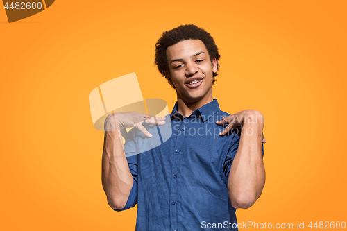 Image of Beautiful male half-length portrait isolated on orange studio backgroud. The young emotional surprised man