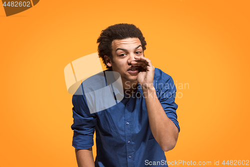 Image of Isolated on orange young casual man shouting at studio