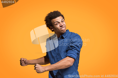 Image of The young emotional angry man screaming on orange studio background