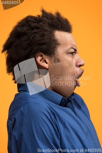 Image of Beautiful male half-length portrait isolated on orange studio backgroud. The young emotional surprised man