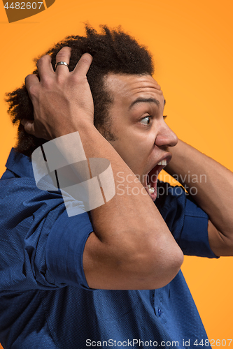 Image of The young emotional angry man screaming on orange studio background