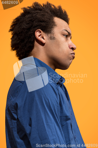 Image of The young emotional angry man screaming on orange studio background