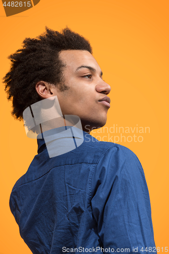 Image of Beautiful male half-length portrait isolated on orange studio backgroud. The young emotional surprised man