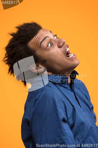 Image of The young emotional angry man screaming on orange studio background