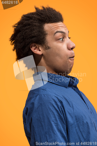 Image of The young attractive man looking suprised isolated on orange