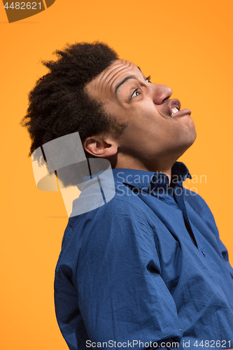 Image of The young emotional angry man screaming on orange studio background