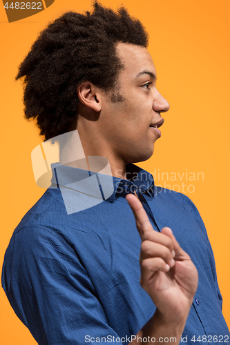 Image of Beautiful male half-length portrait isolated on orange studio backgroud. The young emotional surprised man