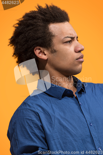 Image of The serious businessman standing against orange background.