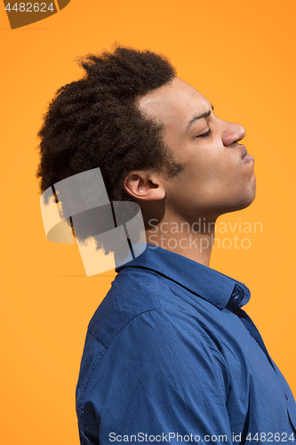 Image of The young emotional angry man screaming on orange studio background