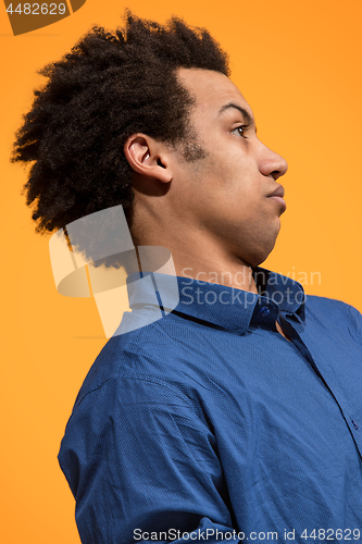 Image of Beautiful male half-length portrait isolated on orange studio backgroud. The young emotional surprised man