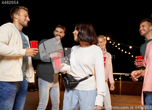 Image of friends with drinks dancing at rooftop party