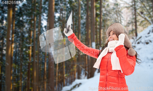 Image of woman in winter fur hat with tablet pc outdoors