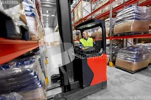 Image of male loader operating forklift at warehouse