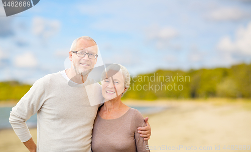 Image of happy senior couple hugging over beach background