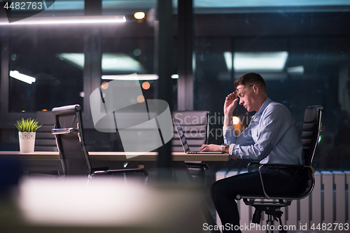 Image of man working on laptop in dark office